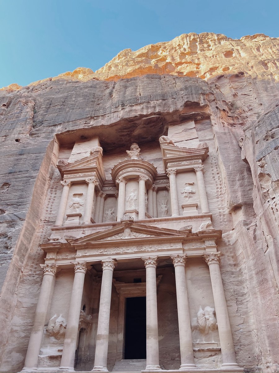 Tall classical-style stone façade carved into a rose sandstone cliff at Petra.