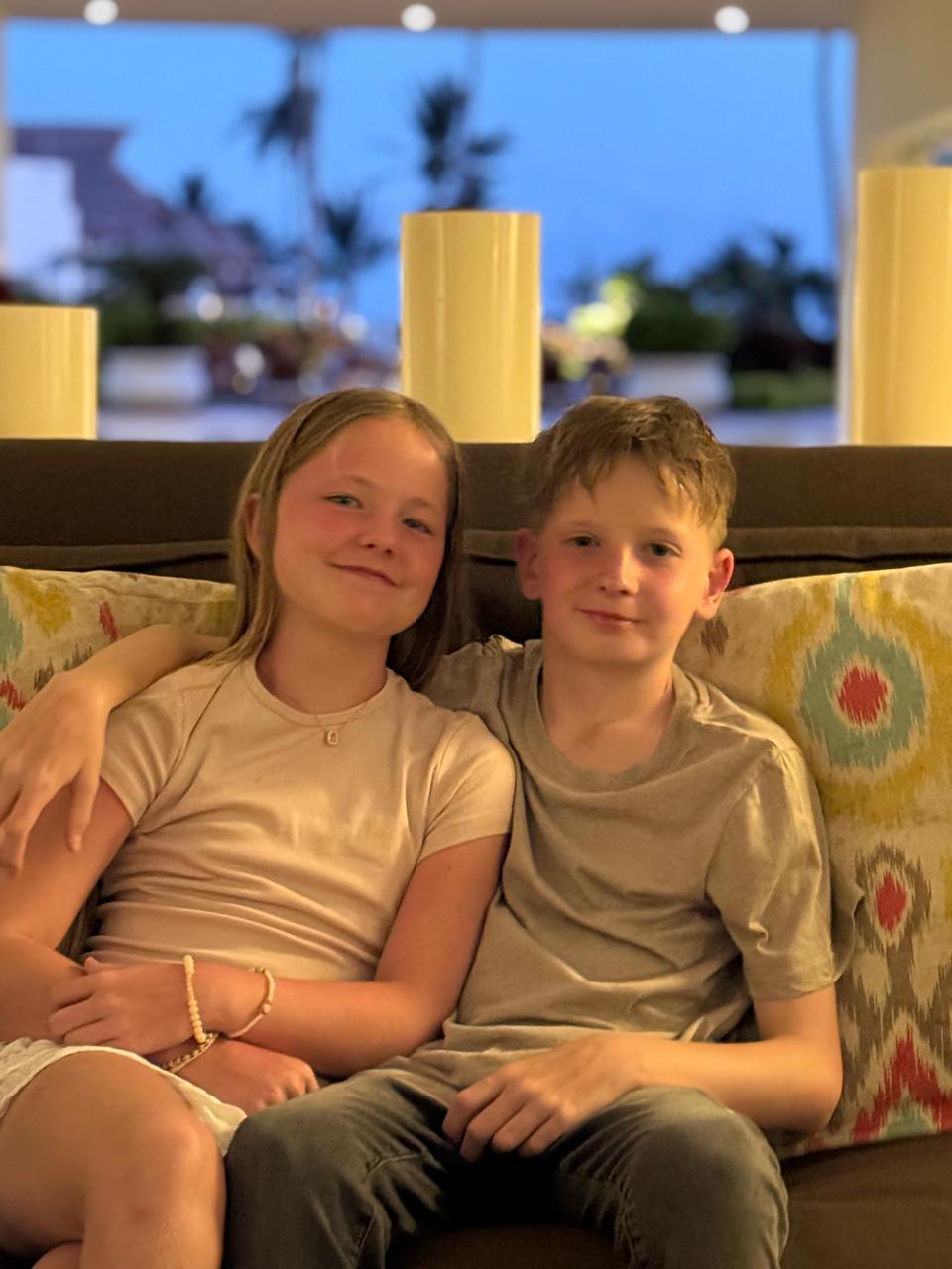 Aimee and her brother sitting together on a sofa