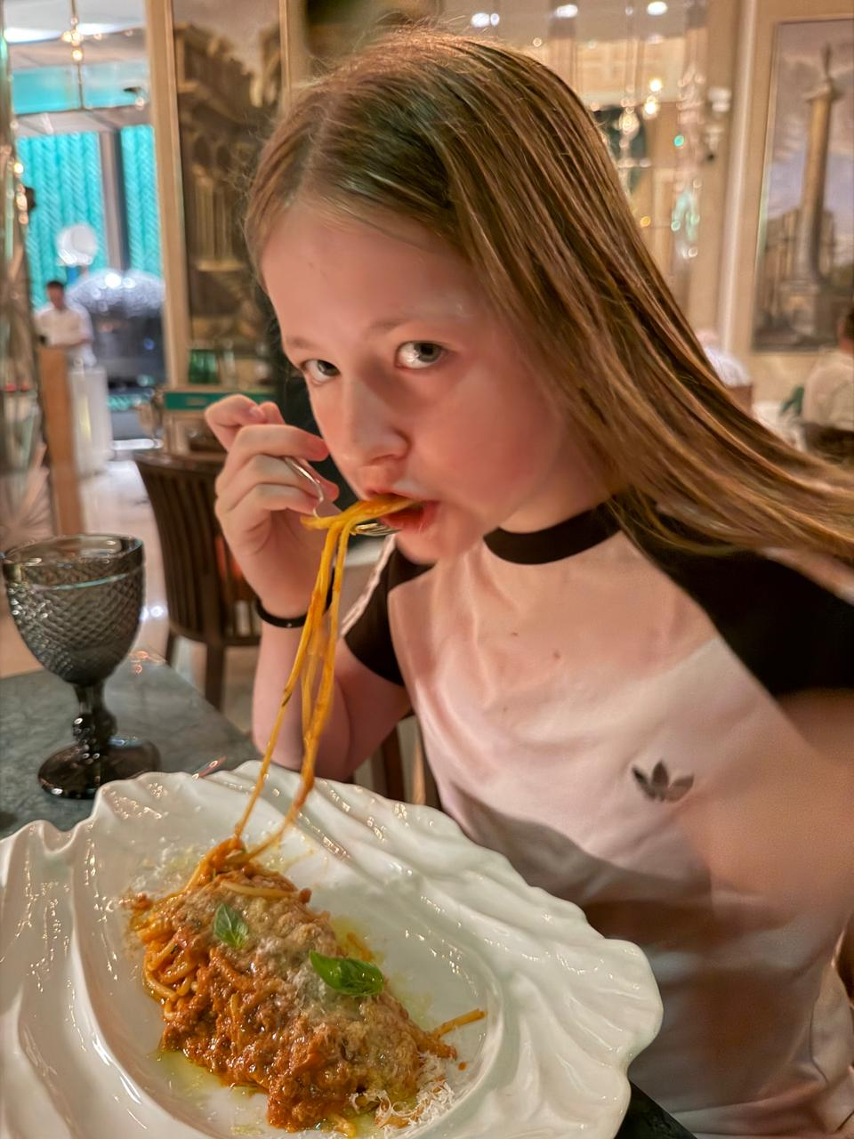 Aimee eating spaghetti bolognese at a restaurant in Dubai, looking at the camera