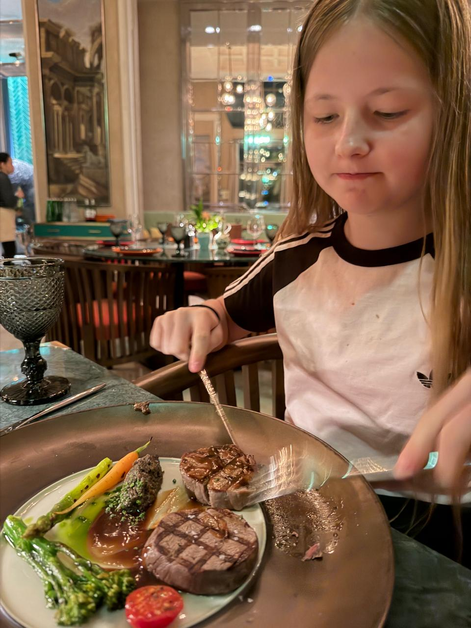 Aimee cutting into a steak with asparagus at a restaurant