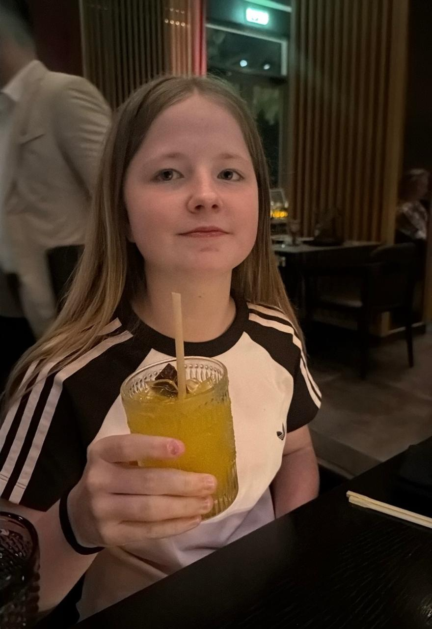 Aimee holding up a glass of juice at a restaurant