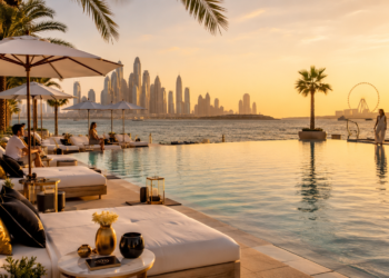 A premium Dubai beach club scene with sunbeds, pool, mocktails, towels, palm trees, sea views and warm golden sunlight.