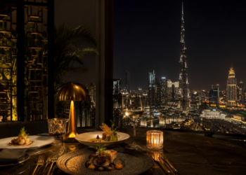 A premium Dubai restaurant table with elegant plates, seafood, pasta, grilled dishes, desserts and warm golden dining room lighting.