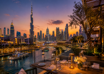 A premium Dubai restaurant table with elegant dishes, glassware, warm lighting and skyline views in the background.