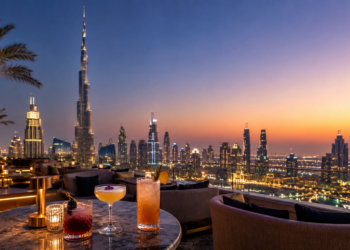A premium Dubai rooftop bar scene with elegant drinks, skyline views, golden sunset light and a modern rooftop lounge setting.