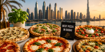 A selection of wood-fired pizzas with fresh toppings on a table overlooking the Dubai skyline and Burj Khalifa at sunset.