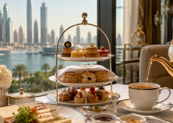 Luxury afternoon tea in Dubai with scones, pastries and tea poured beside soft marina skyline views.