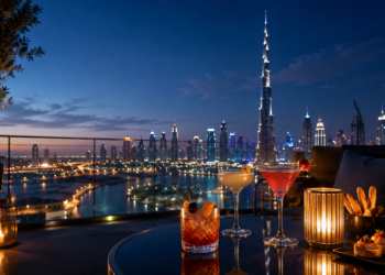 Elegant cocktails on a Dubai rooftop bar at blue hour with the Burj Khalifa and illuminated skyline in the background.