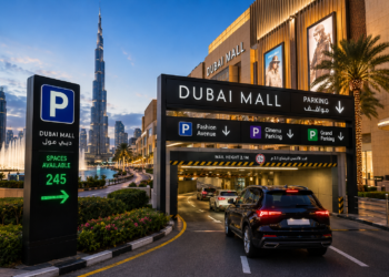 Dubai Mall parking entrance with cars, nearby fountain and Burj Khalifa in Downtown Dubai.