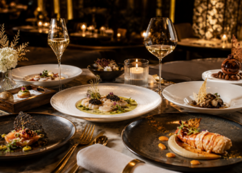 A premium fine dining table with elegant plated dishes, tasting menu courses, gold cutlery and warm luxury restaurant lighting in Dubai.