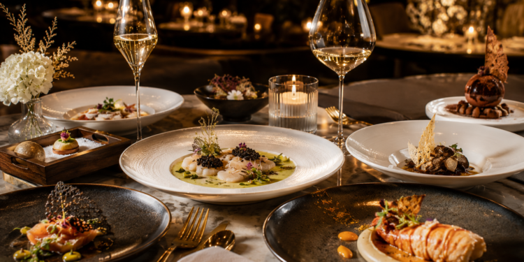 A premium fine dining table with elegant plated dishes, tasting menu courses, gold cutlery and warm luxury restaurant lighting in Dubai.