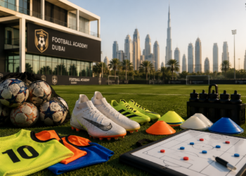 A premium Dubai youth football training scene with football boots, cones, balls, bibs and a modern pitch under golden light.