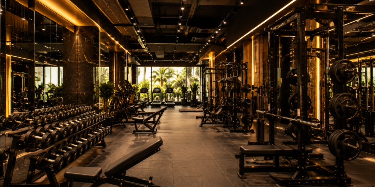 A premium Dubai gym interior with strength equipment, dumbbells, squat racks, cardio machines and warm modern lighting.