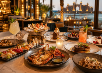 A premium Palm Jumeirah restaurant table with elegant seafood, sushi, steak, pasta, desserts and warm golden lighting.