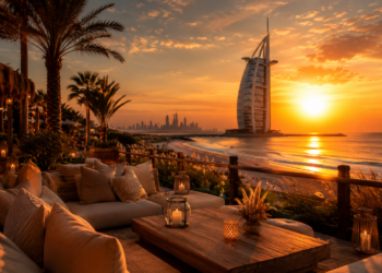 A premium Dubai sunset scene with golden sky, skyline views, beach seating and warm evening lighting.